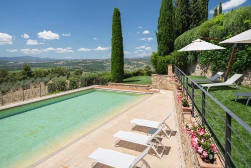 a swimming pool with chairs and umbrellas at Castello Banfi - Il Borgo in Montalcino