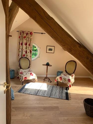 Cette chambre mansardée comprend deux chaises et une table. dans l'établissement Maison d'hôtes et bien-être Ahimsa, à Verrières-le-Buisson