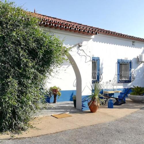 a white building with an arch and a table and chairs at Quinta do Freixo in Reguengos de Monsaraz