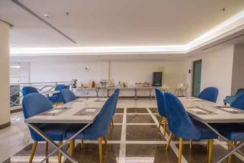 a conference room with tables and blue chairs at The Address Palace Apartments in Dammam