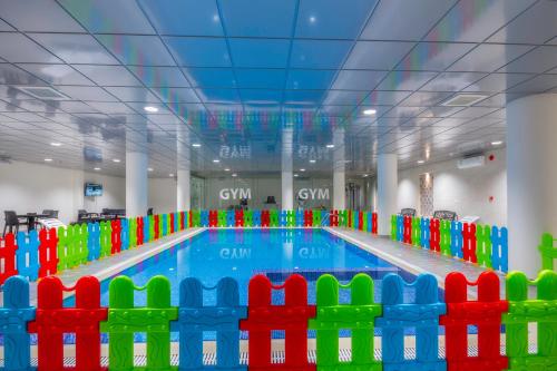 a large swimming pool with colorful chairs around it at The Address Palace Apartments in Dammam