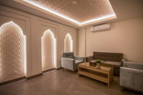 a waiting room with chairs and a table and windows at The Address Palace Apartments in Dammam