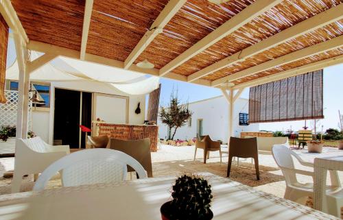 a patio with white chairs and tables and a wooden ceiling at Tenuta Sofia in Otranto