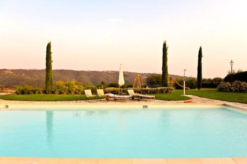einen Pool mit einem Tisch, Stühlen und Bäumen in der Unterkunft Villa Le Ginestre in Parrano