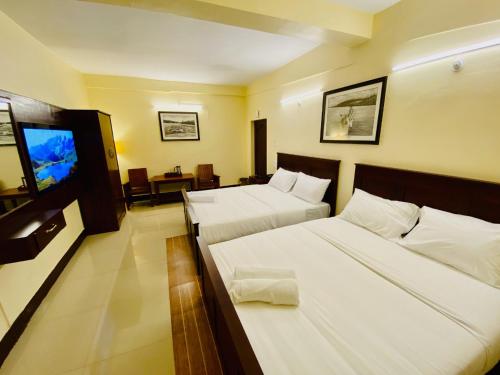 a hotel room with two beds and a flat screen tv at Aakash Rooms and Cottages, in Ooty