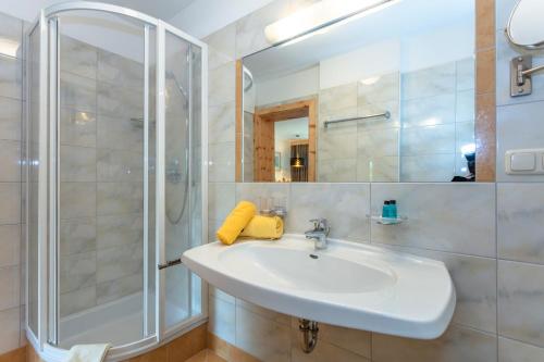 a white bathroom with a sink and a shower at Apartment Gästehaus Luggau in Rauris