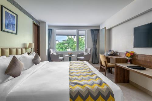 a hotel room with a large bed and a desk at Sapphire Boutique Hotel in Navi Mumbai