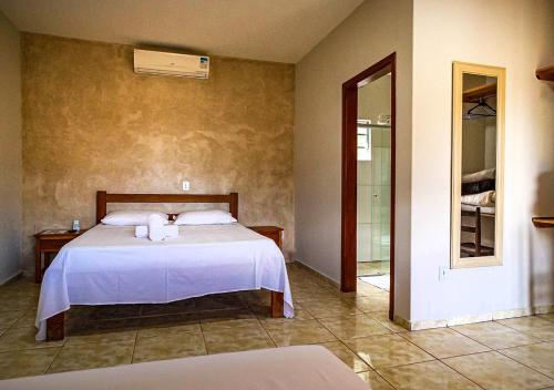 a bedroom with a bed with white sheets and a window at Rancho da Cachaça Pousada in Holambra