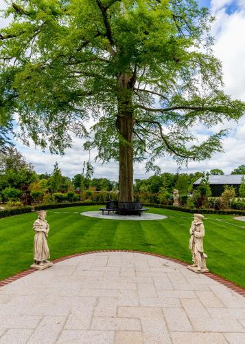 a large tree with two statues in a park at Bective Stud Apartments in Navan