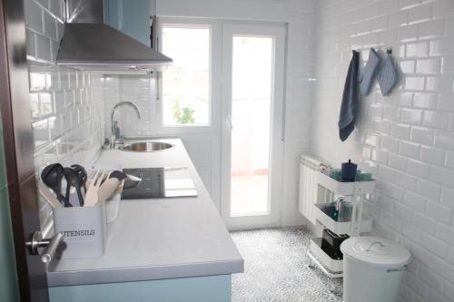 uma cozinha branca com um balcão e um lavatório em Jovellanos Playa em Ribadesella