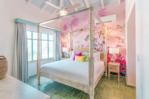a bedroom with a canopy bed with pink walls at Boardwalk Boutique Hotel Aruba in Palm-Eagle Beach