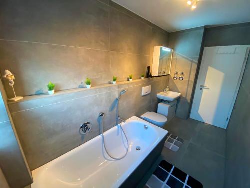 a bathroom with a tub and a toilet and a sink at Ferienwohnung Augsburg 1 in Augsburg