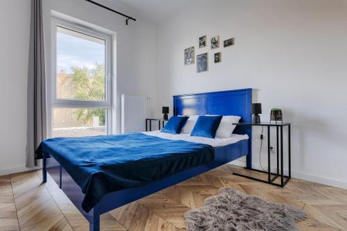 sypialnia z niebieskim łóżkiem i oknem w obiekcie Ilumino by LookAp w Łodzi