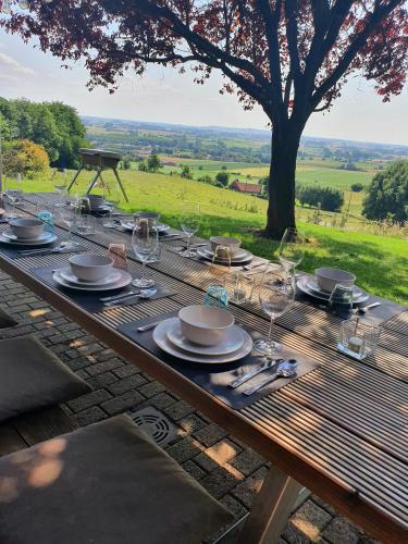 a wooden table with plates and wine glasses on it at Villa de la Sablière in Amougies