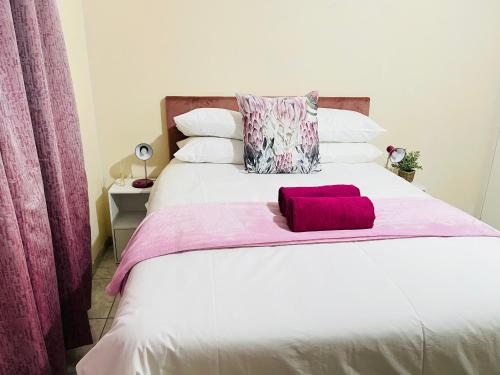 a bedroom with a white bed with a red pillow at The Home in Richards Bay