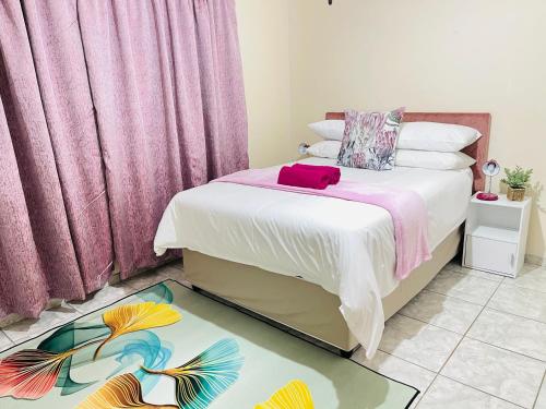 1 dormitorio con 1 cama con cortinas rosas en The Home en Richards Bay