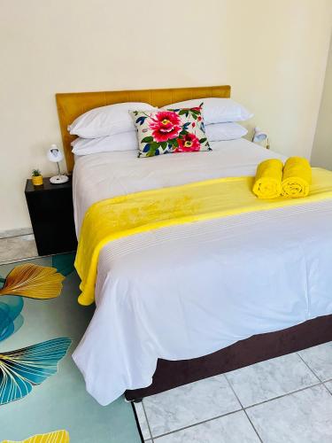 a white bed with yellow blankets and pillows on it at The Home in Richards Bay