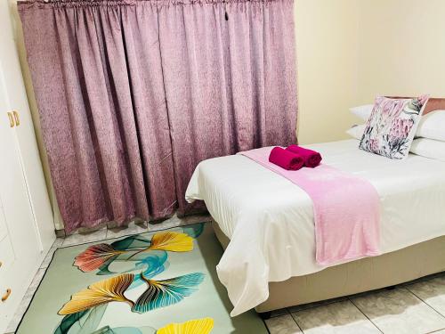 two beds in a room with a pink curtain at The Home in Richards Bay