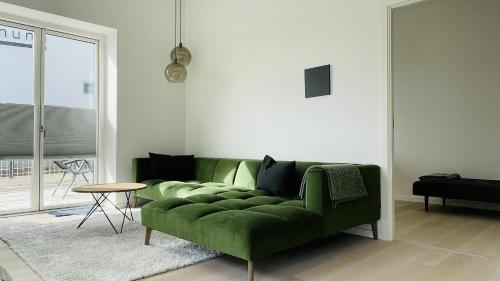 a living room with a green couch and a table at ApartmentInCopenhagen Apartment 1460 in Copenhagen