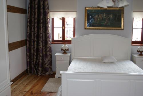 a bedroom with a white bed and two windows at Pokoje Gościnne u Eweliny in Bogatynia