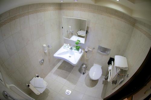 a bathroom with a sink and a toilet and a mirror at Capsis Hotel Thessaloniki in Thessaloniki
