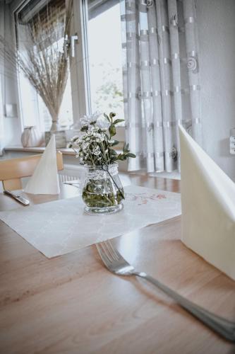 a vase of flowers sitting on a table with a laptop at Landgasthof Hotel Will in Neuenstein
