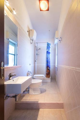 a white bathroom with a sink and a toilet at La terrazza di S'Oru 'e Mari in Quartu SantʼElena