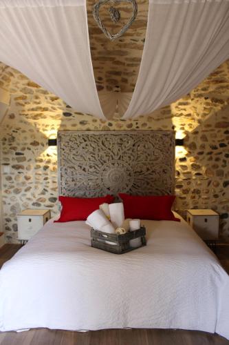 Schlafzimmer mit einem weißen Bett und roten Kissen in der Unterkunft Le Mas Charamèlia in Saint-Victor-de-Malcap