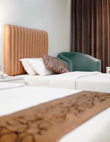a hotel room with two beds and a green chair at White Orchid in Cox's Bazar