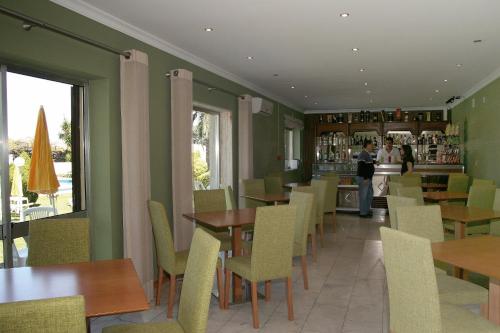 a restaurant with tables and chairs and a bar at Arcada Hotel in Tocha