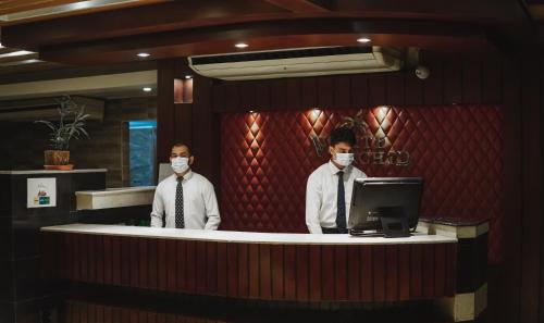 two men wearing face masks standing at a counter at White Orchid in Cox's Bazar