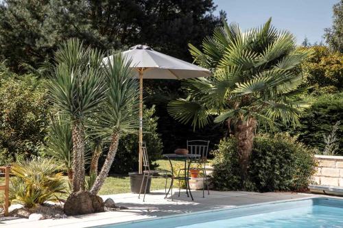 una sombrilla y una mesa junto a la piscina en Merveilleuses chambres d'hôtes à Panazol en Panazol