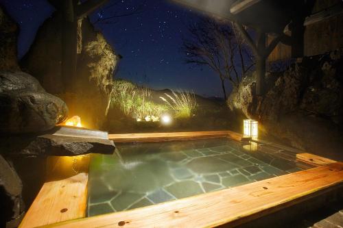 a jacuzzi tub with a wooden deck and lights at Sawaemon in Chino