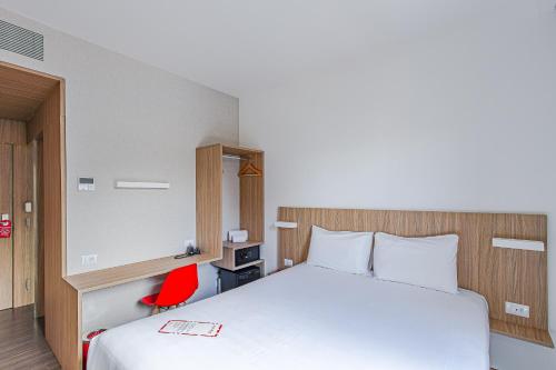 a hotel room with a bed and a red chair at Hotel Moov Curitiba in Curitiba