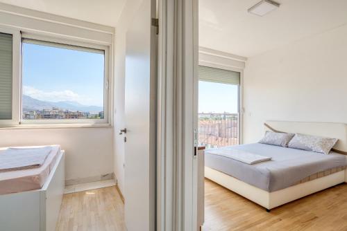 a white bedroom with a bed and a window at Apartman Marko in Podgorica