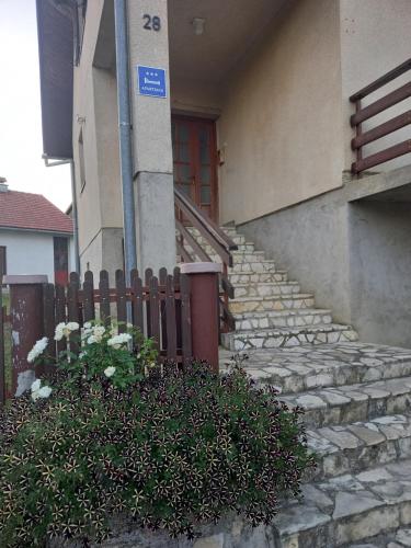 a house with a staircase leading to a red door at Apartman Ivano in Gospić