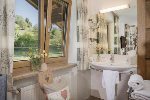 ein Bad mit einem Waschbecken, einem Spiegel und einem Fenster in der Unterkunft Café Pension Koller in Brixen im Thale
