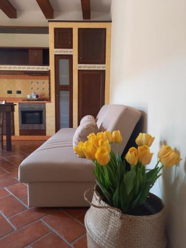 een woonkamer met een bank en een vaas met gele bloemen bij Appartamento F&M in Castelnuovo Magra