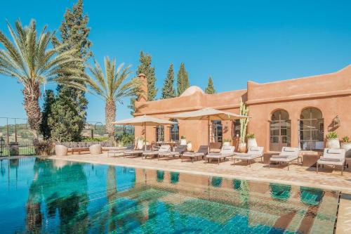 a house with a swimming pool and palm trees at Le Jardin des Douars in Ghazoua