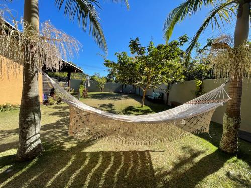 a hammock hanging between two palm trees in a yard at Pousada Lagoa do Rosa in Praia do Rosa