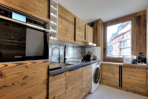 une cuisine avec des armoires en bois et une laveuse et une sécheuse dans l'établissement Appartement familial au pied de la télécabine 4*, à Saint-Gervais-les-Bains