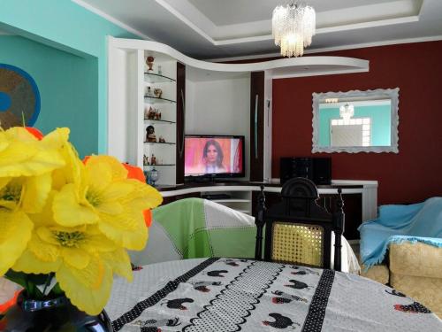 a dining room with a table with yellow flowers and a tv at Pousada Souza in Florianópolis