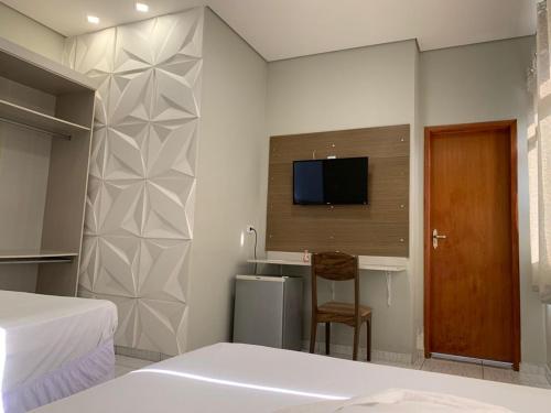 um quarto com uma secretária e uma televisão na parede em Hotel Lider em Paranaguá