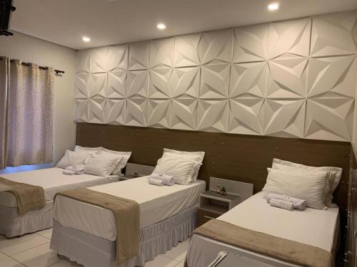 a room with two beds and a wall at Hotel Lider in Paranaguá
