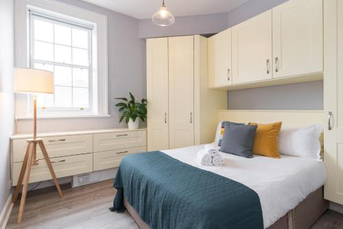 a bedroom with a bed with white cabinets and a window at Dame Street - Irish Stay Group in Dublin