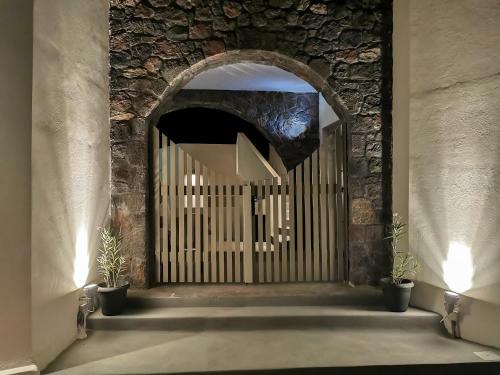 a gate in a stone wall with two potted plants at Noir Santorini in Monolithos