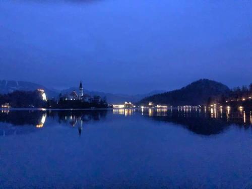 a large body of water at night with a city at Sovica in Bled