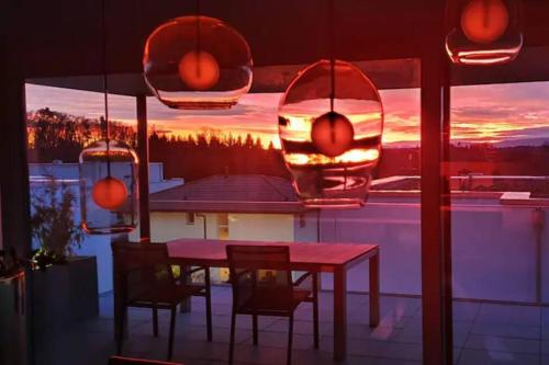 a table and chairs on a balcony with a sunset at Luxusloft mit warmem Outdoor Whirlpool in Mühleberg