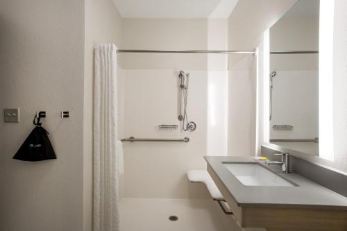 a white bathroom with a sink and a mirror at Candlewood Suites Apex Raleigh Area, an IHG Hotel in Apex