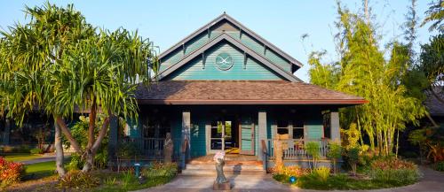 a small blue house with palm trees in front of it at Lumeria Maui, Educational Retreat Center in Makawao